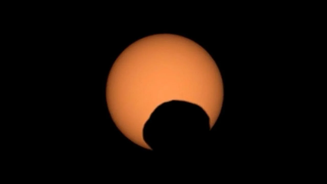 A missão Perseverance da NASA registrou o Eclipse Solar em Marte sendo o trânsito de Fobos, uma das duas luas de Marte, passando diante do Sol no 1.285º dia marciano. O evento foi capturado com detalhes impressionantes, mostrando o Sol sendo obscurecido pela lua marciana Fobos enquanto o rover Perseverance observa o fenômeno cósmico em Marte.