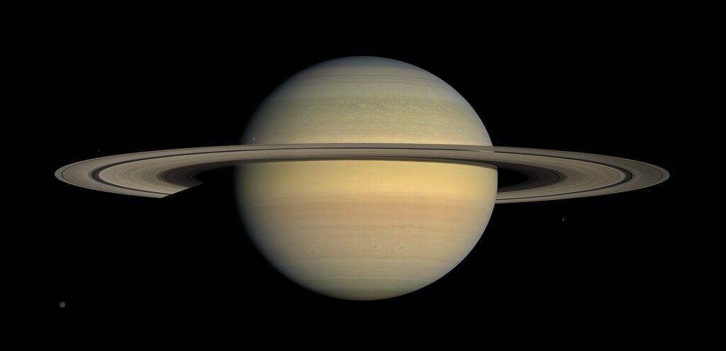 Saturno, capturado pelo Telescópio Espacial Hubble, mostrando o planeta com seus icônicos anéis e várias das suas luas mais importantes, como Titã, Encélado, Mimas e Dione. O contraste entre os anéis brilhantes de Saturno e as luas visíveis em torno do planeta oferece uma visão impressionante da complexidade do sistema de Saturno