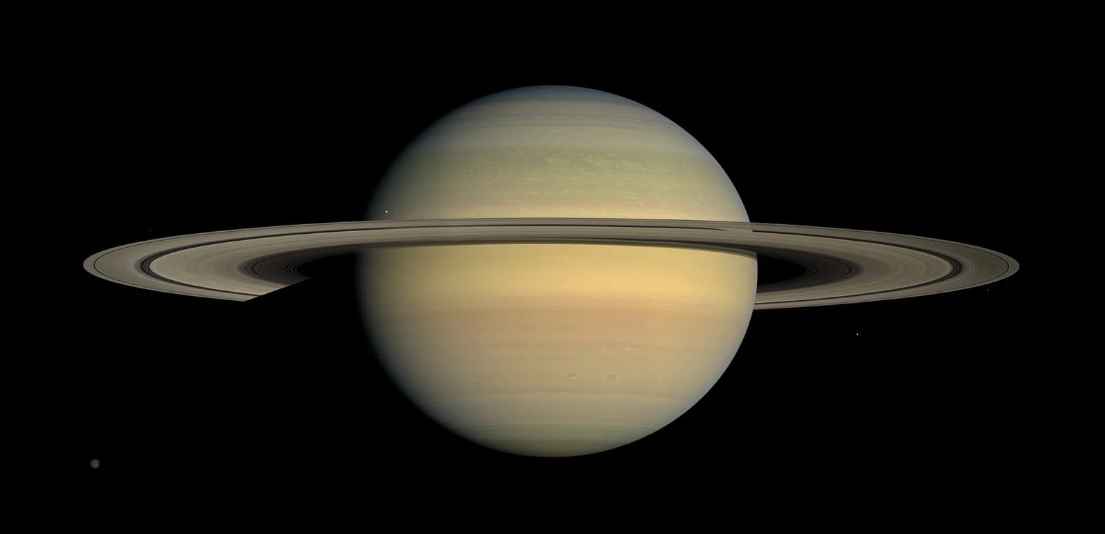 Saturno, capturado pelo Telescópio Espacial Hubble, mostrando o planeta com seus icônicos anéis e várias das suas luas mais importantes, como Titã, Encélado, Mimas e Dione. O contraste entre os anéis brilhantes de Saturno e as luas visíveis em torno do planeta oferece uma visão impressionante da complexidade do sistema de Saturno