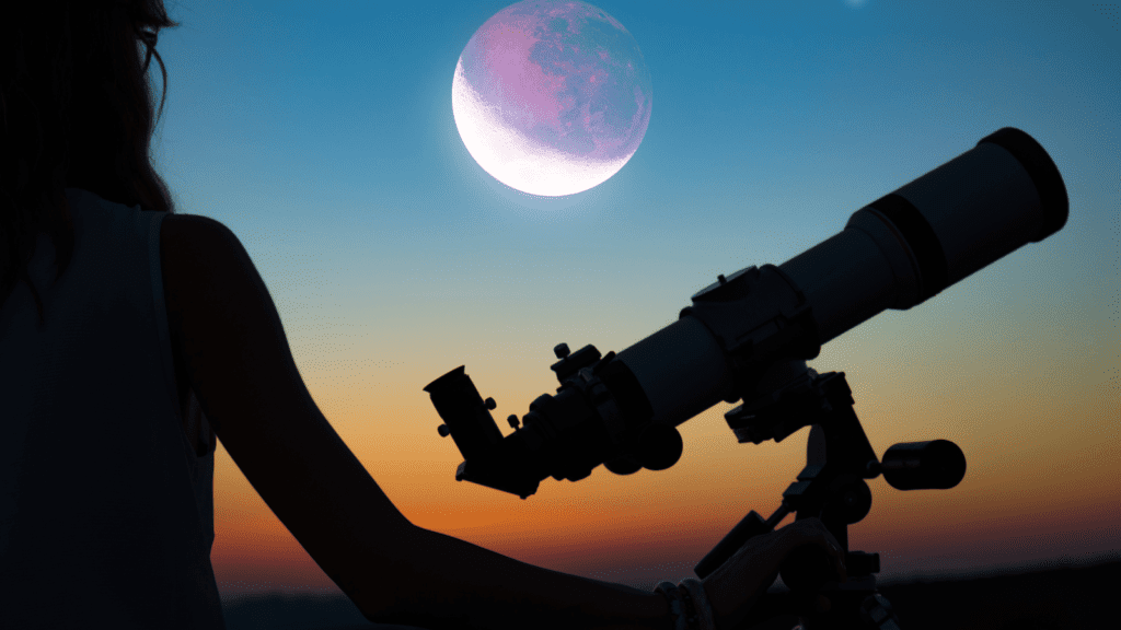 Silhueta de uma mo&ccedil;a observando o c&eacute;u ao lado de um telesc&oacute;pio, ao fundo uma ceualaranjado mostrando o entardecer alaranjado no ceu a lua entrando em uma eclipse, essa cena representa busca da resposta de "O que &eacute; Astronomia?" o que h&aacute; de novo no universo.