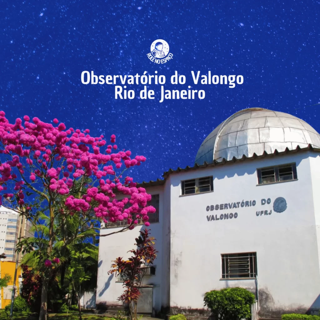bservatório do Valongo, no Rio de Janeiro, com a cúpula metálica visível e a estrutura do prédio em branco. O edifício está ao lado de uma árvore com flores de um rosa vibrante, enquanto o céu estrelado ao fundo destaca a importância do local para a pesquisa astronômica.
