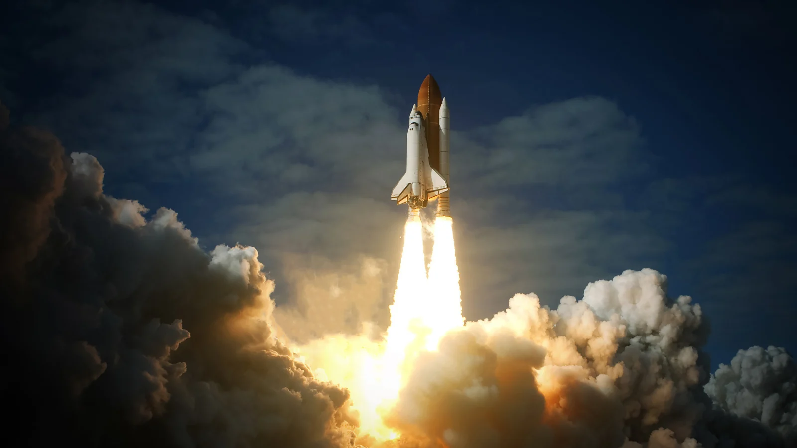 Lançamento de um ônibus espacial, com a enorme potência dos foguetes gerando uma explosão de fogo e fumaça enquanto o veículo ascende em direção ao céu. O ônibus espacial é visto no início de sua trajetória, com a separação dos boosters laterais e o veículo se afastando da base de lançamento. A palavra-chave "Lançamento espacial" é representada pelo evento dinâmico do lançamento.