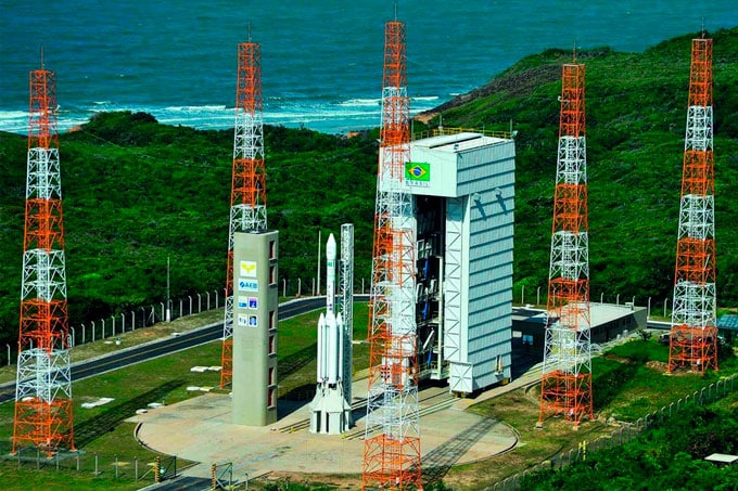 Vista da Base de Lançamento de Alcântara, localizada entre a floresta e o mar. A imagem mostra a infraestrutura de lançamento cercada por vegetação exuberante, com o vasto oceano ao fundo. Não é a Base da NASA no Brasil,, mas é a Fachada do prédio da Agência Espacial Brasileira (AEB), com uma coloração azul escuro. Há uma marquise com o nome 'AGÊNCIA ESPACIAL BRASILEIRA' em letras garrafais e uma placa cromada com o logo da AEB. muitos acham que é uma Base da NASA no Brasil, mas na verdade a base é brasileira.
