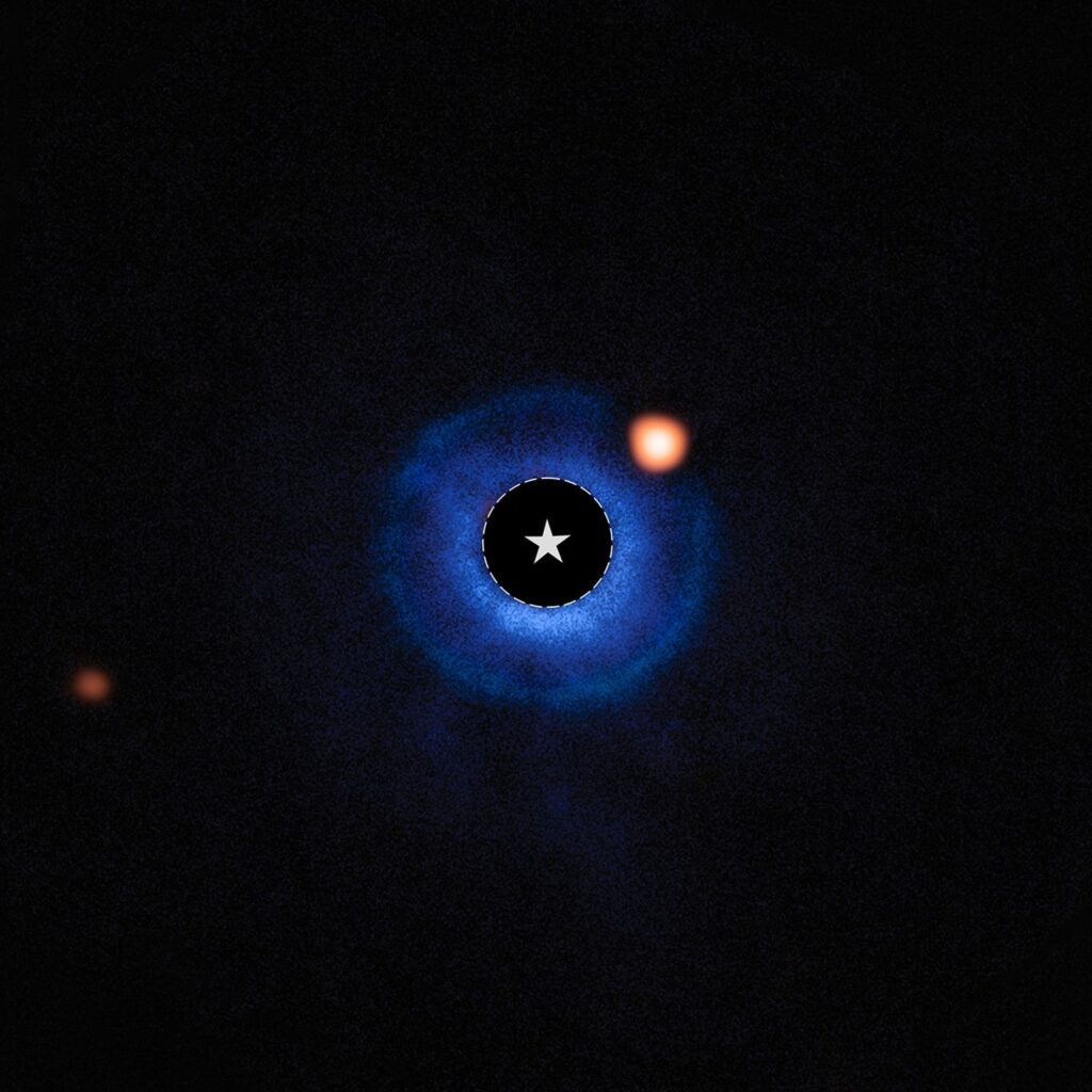 Imagem do sistema estelar TWA 7 com dados combinados do Telescópio Espacial James Webb e do Very Large Telescope. A estrela TWA 7 está no centro, marcada por um círculo e símbolo de estrela. Dados em azul mostram o disco de detritos ao redor da estrela, enquanto pontos laranja indicam objetos no sistema: o ponto brilhante no canto superior direito é o exoplaneta candidato TWA 7 b dentro do disco, e o ponto laranja à esquerda é uma estrela de fundo sem relação.