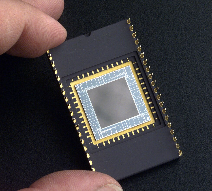 Mão segurando módulos de CCDs, dispositivos de imageamento digital usados em fotografia, satélites, equipamentos médico-hospitalares e em astronomia para fotometria, óptica e espectroscopia UV.