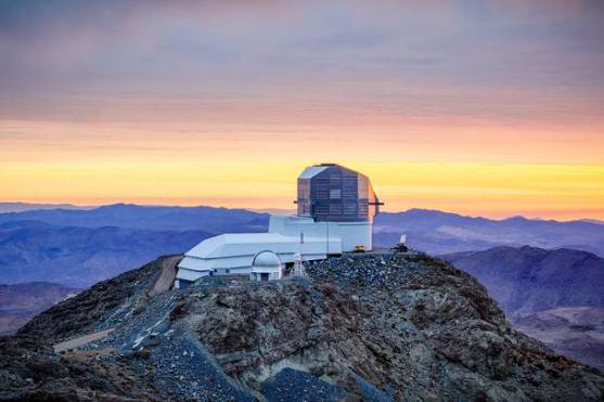 Vista panorâmica do Observatório Vera C. Rubin ao entardecer, localizado no alto do Cerro Pachón, com as montanhas chilenas ao fundo.