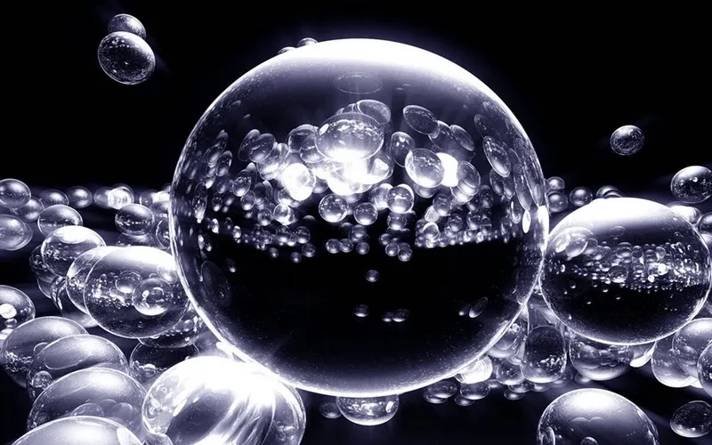 Imagem com fundo preto mostrando gotículas de água em destaque, com foco nítido nas pequenas partículas de água dentro das gotículas maiores, ressaltando a textura e o brilho das moléculas líquidas.
