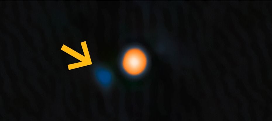 Imagem da estrela Betelgeuse em tons amarelo-avermelhados. Uma seta amarela destaca sua estrela companheira próxima, visível como um ponto azul tênue. Dados: NASA, JPL e NOIRLab; visualização: NOIRLab.