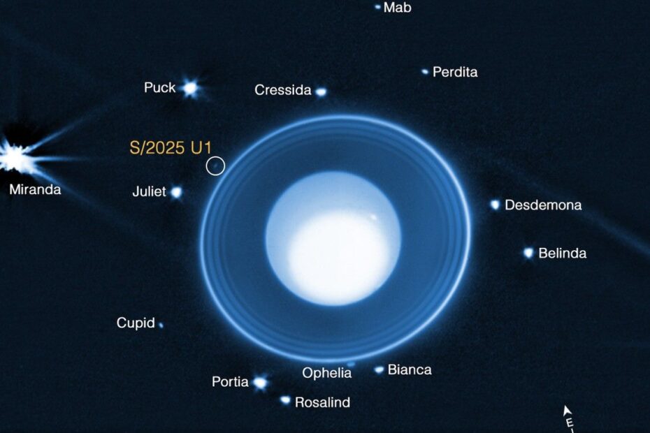 Imagem de Urano pelo Telescópio James Webb em 6 de fevereiro de 2023. Urano aparece azul-claro sobre fundo preto, com uma grande mancha branca e dois pontos brilhantes. Ao redor, há anéis verticais e seis luas visíveis: Puck, Ariel, Miranda, Umbriel, Titânia e Oberon. Pontos alaranjados tênues aparecem ao fundo. Filtros NIRCam usados: F140M (azul) e F300M (laranja)."
