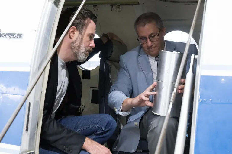 Dois pesquisadores de heliofísica são vistos na porta da aeronave B200 King Air da NASA segurando e discutindo um modelo