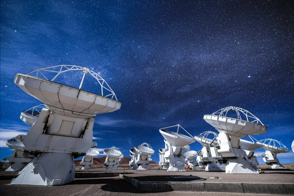 As antenas do observatório ALMA em configuração compacta, localizadas a 5000 metros de altitude no Planalto de Chajnantor, apontando para o céu em uma noite estrelada. Crédito: Alex Pérez/ALMA.