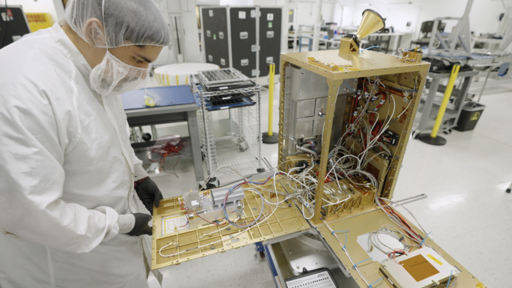 Um engenheiro inspeciona o satélite Starcloud-1, planejado para lançamento em novembro. O módulo prateado dentro do satélite abriga a GPU NVIDIA H100. Vídeo cortesia da Starcloud.
