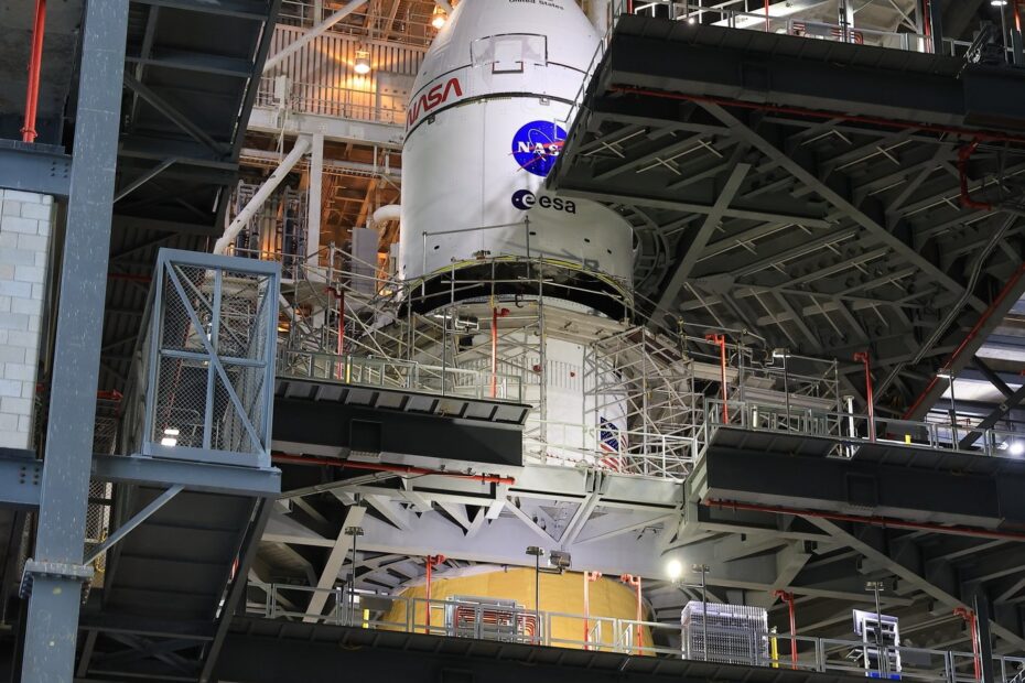 Vista de longe da nave Orion sendo elevada pelo guindaste no local de lançamento, durante o processo de montagem no foguete SLS para a missão Artemis 2. Créditos: NASA