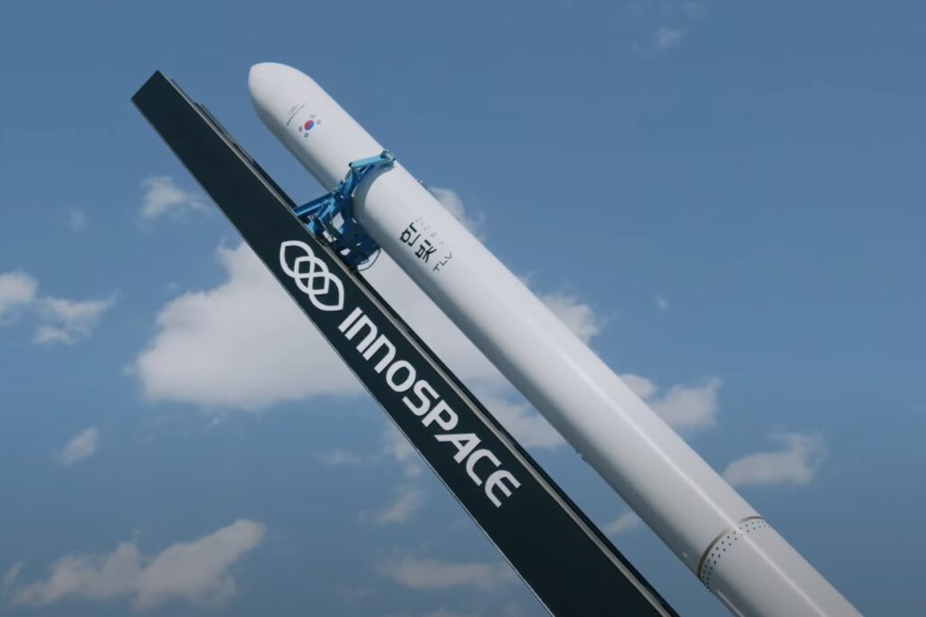 Foguete Hanbit-Nano da empresa sul-coreana Innospace em posição de lançamento, destacando seu corpo branco e logotipos, pronto para decolar.
