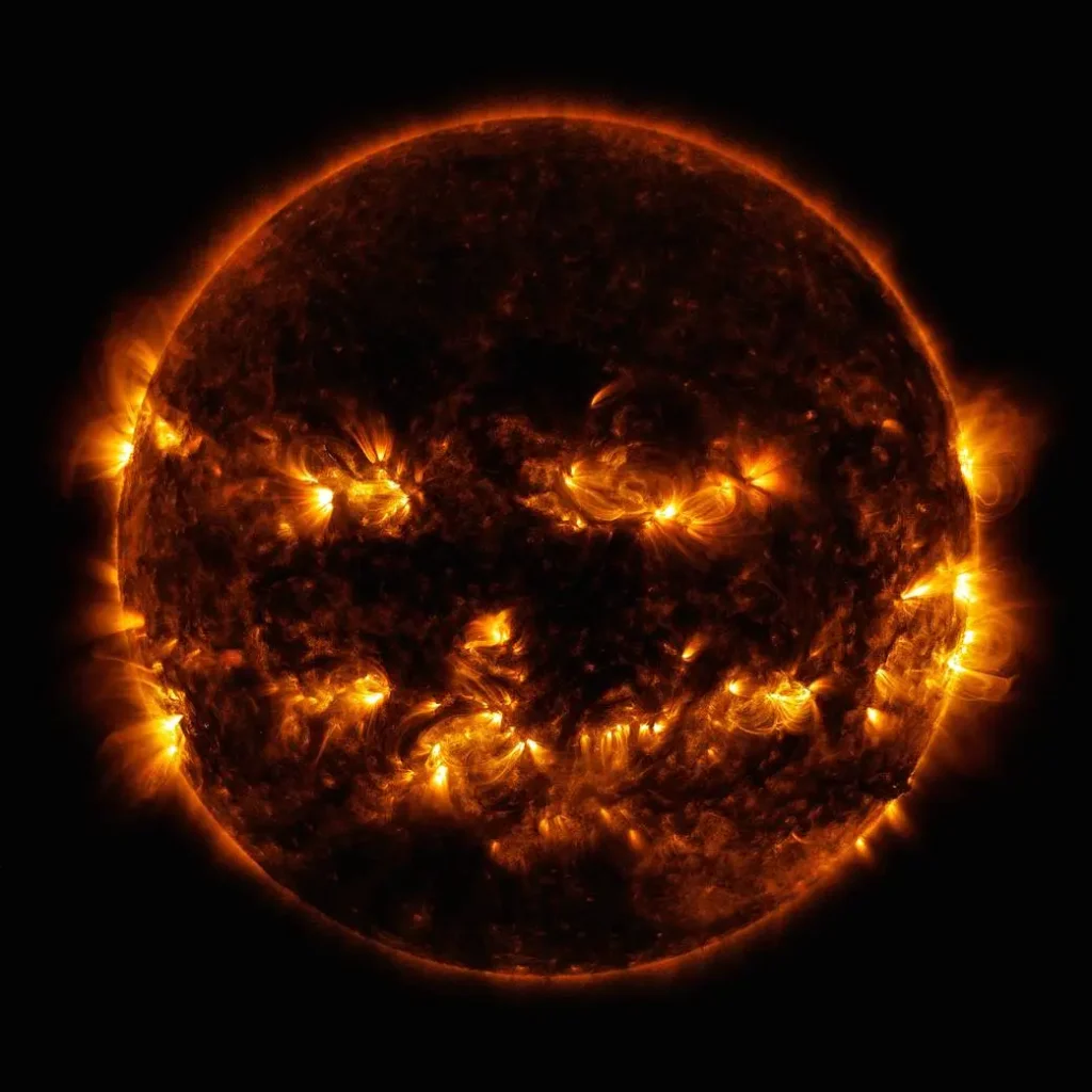 Regiões ativas no Sol combinam-se formando uma face que lembra uma abóbora de Halloween. A imagem foi capturada pelo Solar Dynamics Observatory usando luzes de 171 e 193 angstroms, destacando áreas de intensa emissão de energia e campos magnéticos complexos