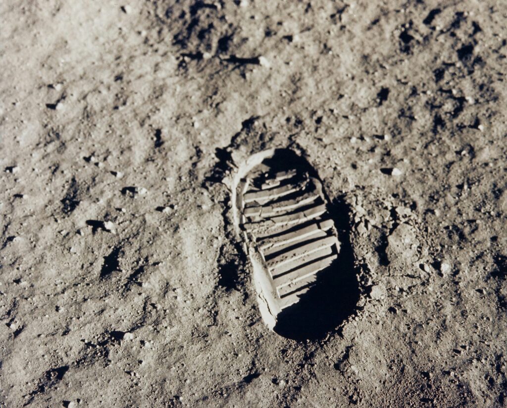 Pegada bem definida de Neil Armstrong astronauta da Apollo 11 na superfície da Lua, destacando os sulcos da bota no solo poeirento e granular do regolito lunar. A iluminação lateral realça os detalhes da marca deixada na história da exploração espacial.