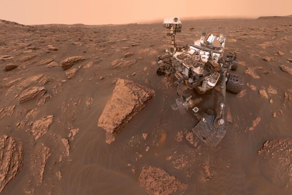 Autorretrato do rover Curiosity em Marte durante uma tempestade de poeira, com o ambiente ao redor escurecido pela baixa visibilidade no Cratera Gale. A imagem foi capturada pela câmera MAHLI no Sol 2082. Credit: NASA/JPL-Caltech/MSSS