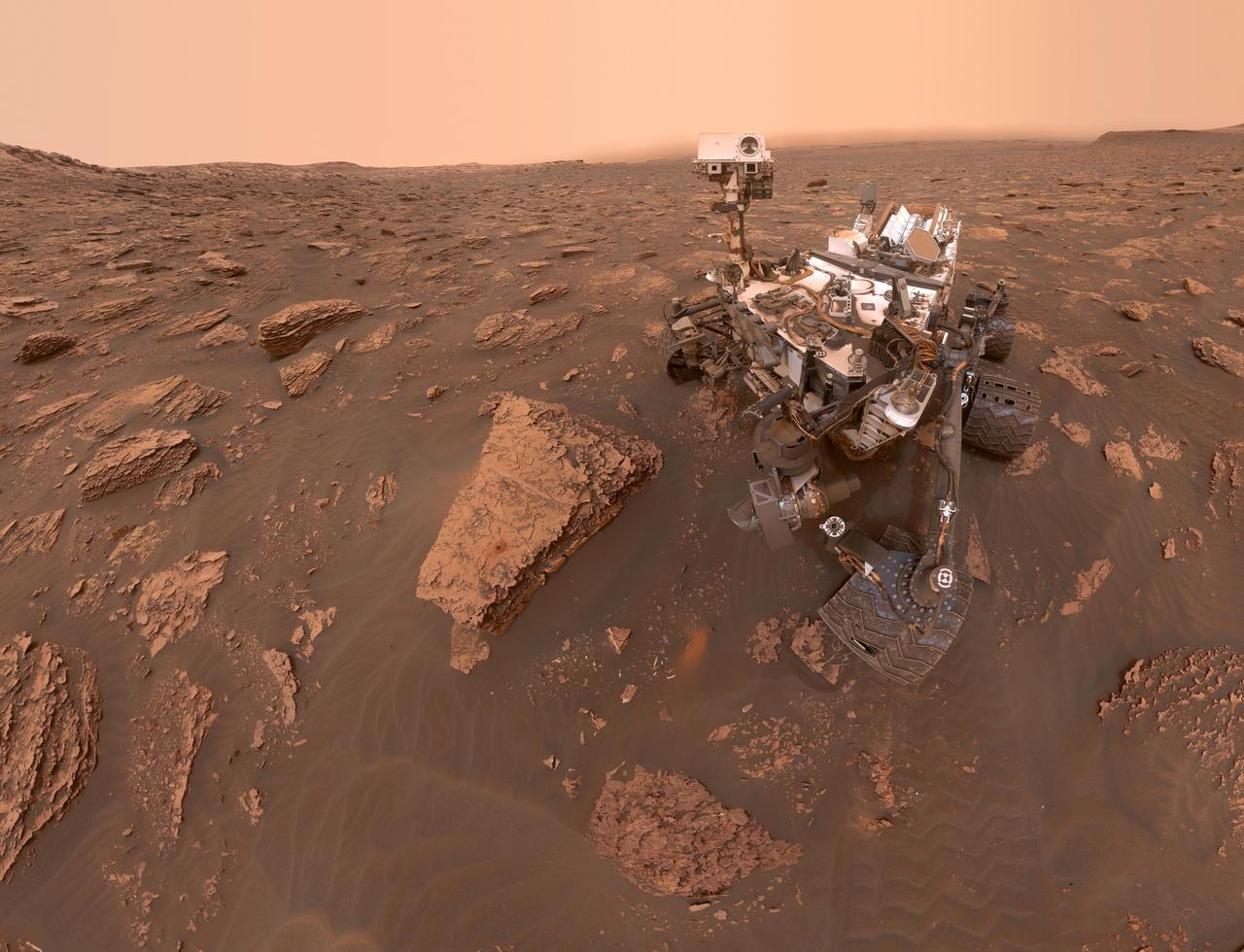 Autorretrato do rover Curiosity em Marte durante uma tempestade de poeira, com o ambiente ao redor escurecido pela baixa visibilidade no Cratera Gale. A imagem foi capturada pela câmera MAHLI no Sol 2082. Credit: NASA/JPL-Caltech/MSSS