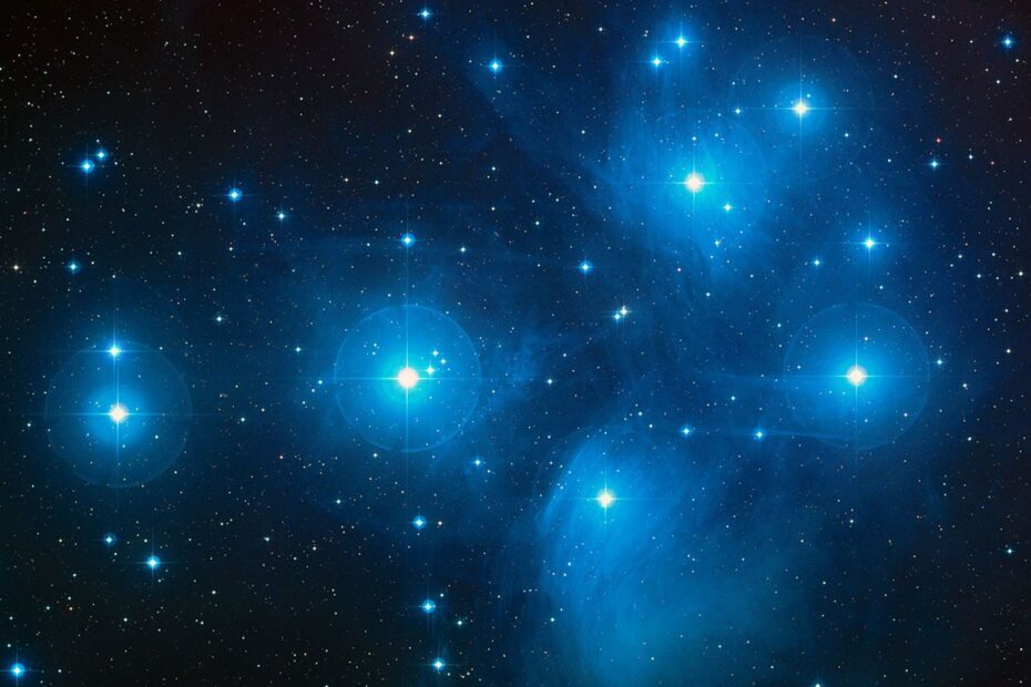 Imagem colorida das Plêiades mostrando estrelas jovens e azuladas espalhadas pela constelação de Touro, capturadas pelo telescópio Schmidt do Observatório Palomar. As estrelas brilhantes do aglomerado, a cerca de 430 anos-luz, aparecem nitidamente dispersas no céu. Crédito: NASA/ESA/AURA/Caltech.