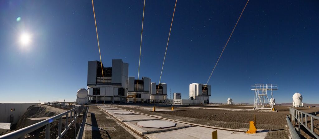 Quatro feixes de laser amarelos são lançados simultaneamente dos telescópios do Observatório de Paranal, no Chile, iluminando o céu noturno como parte do projeto GRAVITY+ do ESO.Créditos: ESO / G. Hüdepohl