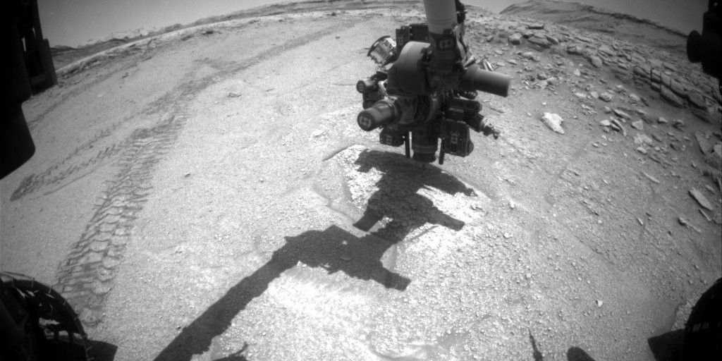 Imagem em preto e branco capturada pela câmera Front Hazcam do rover Curiosity mostrando o início da atividade de perfuração no local “Valle de la Luna”. O braço robótico aparece estendido enquanto o rover realiza o procedimento no Sol 4693.Créditos: NASA/JPL-Caltech