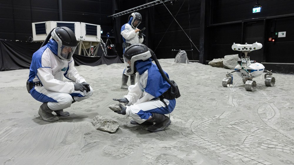 Preparando um experimento na instalação LUNA: pesquisadores avaliam a composição de rochas usando um espectrômetro especial, fundamental para identificar pistas associadas à presença de água. Os rovers precisam reconhecer e examinar essas rochas de forma autônoma. Na instalação LUNA, o DLR testa instrumentos e robôs desenvolvidos para localizar gelo de água na Lua.
Crédito: © DLR. All rights reserved.