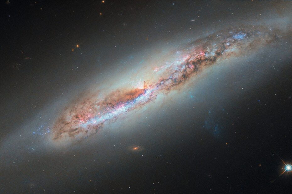 Imagem do Telescópio Espacial Hubble mostrando a galáxia espiral NGC 4388 vista quase de perfil, com uma pluma de gás ionizado sendo arrancada do disco enquanto a galáxia se move pelo aglomerado de Virgem.