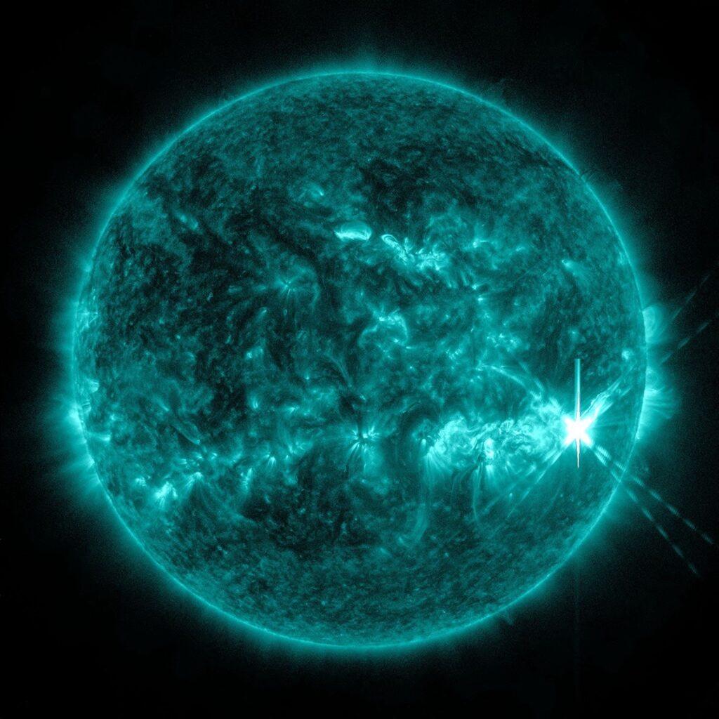Erupção solar Classe X capturada pelo Solar Dynamics Observatory da NASA em 8 de dezembro de 2025, mostrando um flash brilhante de material extremamente quente em luz ultravioleta extrema colorida em tons de teal.