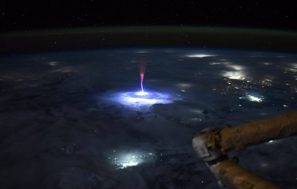Sprites vermelhos registrados a partir da Esta&ccedil;&atilde;o Espacial Internacional, mostrando descargas el&eacute;tricas vermelhas na alta atmosfera terrestre acima de uma regi&atilde;o de tempestades noturnas.