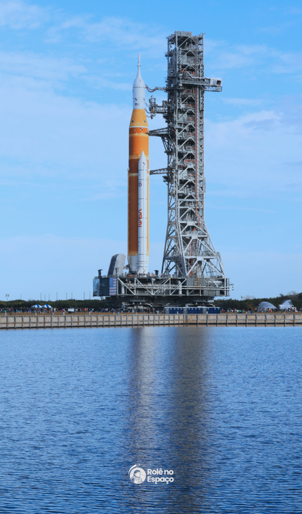 Vista lateral do foguete SLS da missão Artemis II acoplado à torre de lançamento, pronto para os próximos testes antes do voo tripulado. Crédito: NASA.