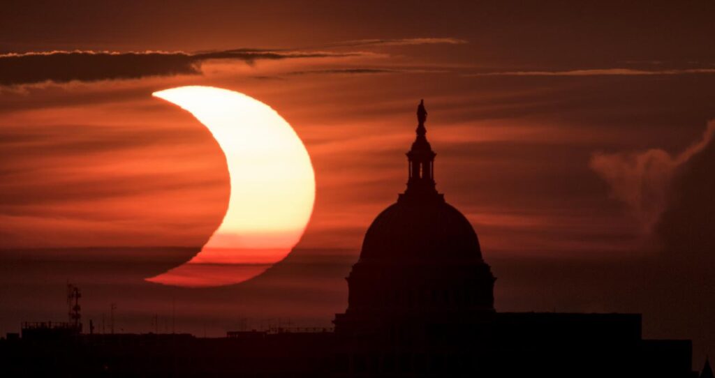 Eclipse solar parcial observado ao nascer do Sol ao lado do Capitólio dos Estados Unidos, em Arlington, Virgínia, em 10 de junho de 2021, com parte do disco solar encoberto pela Lua.