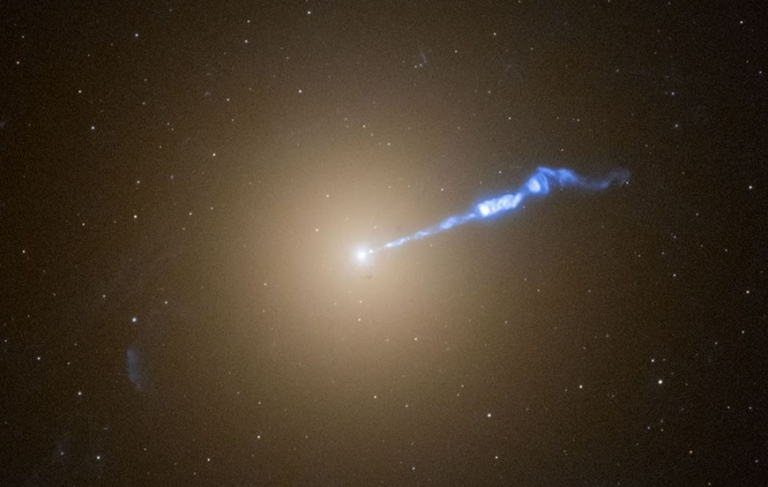 Imagem do Telescópio Espacial Hubble da galáxia elíptica gigante M87, mostrando o jato relativístico brilhante que se estende por cerca de 3.000 anos-luz a partir do buraco negro supermassivo em seu núcleo.