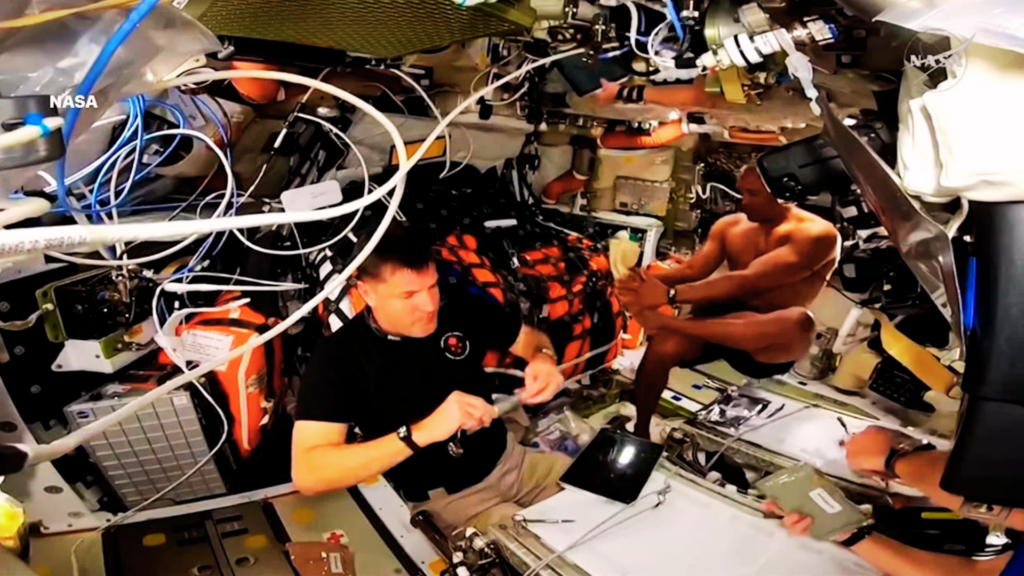 Astronauta Victor Glover realizando higiene pessoal dentro da nave Orion durante a missão Artemis II em ambiente de microgravidade