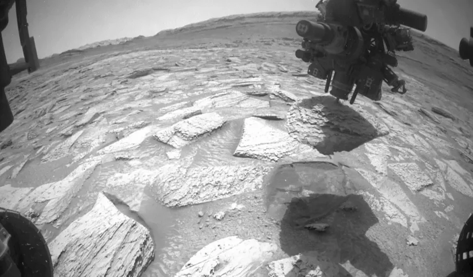Frame de animação mostra a broca do rover Curiosity presa em uma rocha na superfície de Marte durante operação de perfuração.