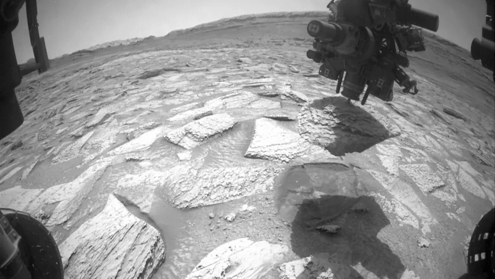 Frame de animação mostra a broca do rover Curiosity presa em uma rocha na superfície de Marte durante operação de perfuração.